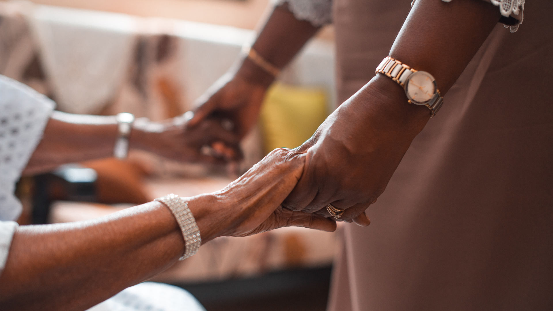 Caregiver gently holding an older patient's hand, offering comfort and support in a healthcare setting.